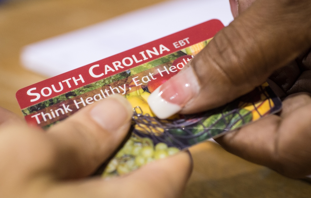 Two hands holding South Carolina EBT card.